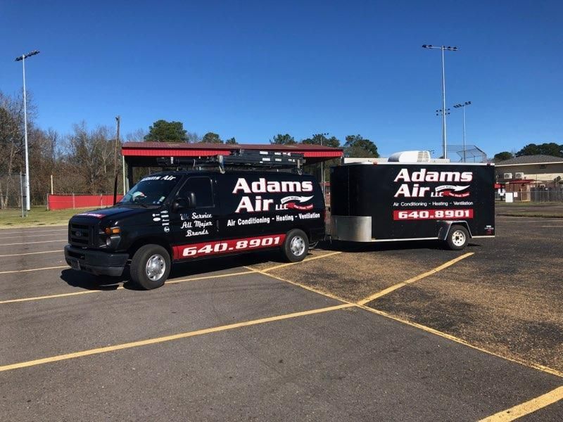 Two adams air trucks are parked in a parking lot