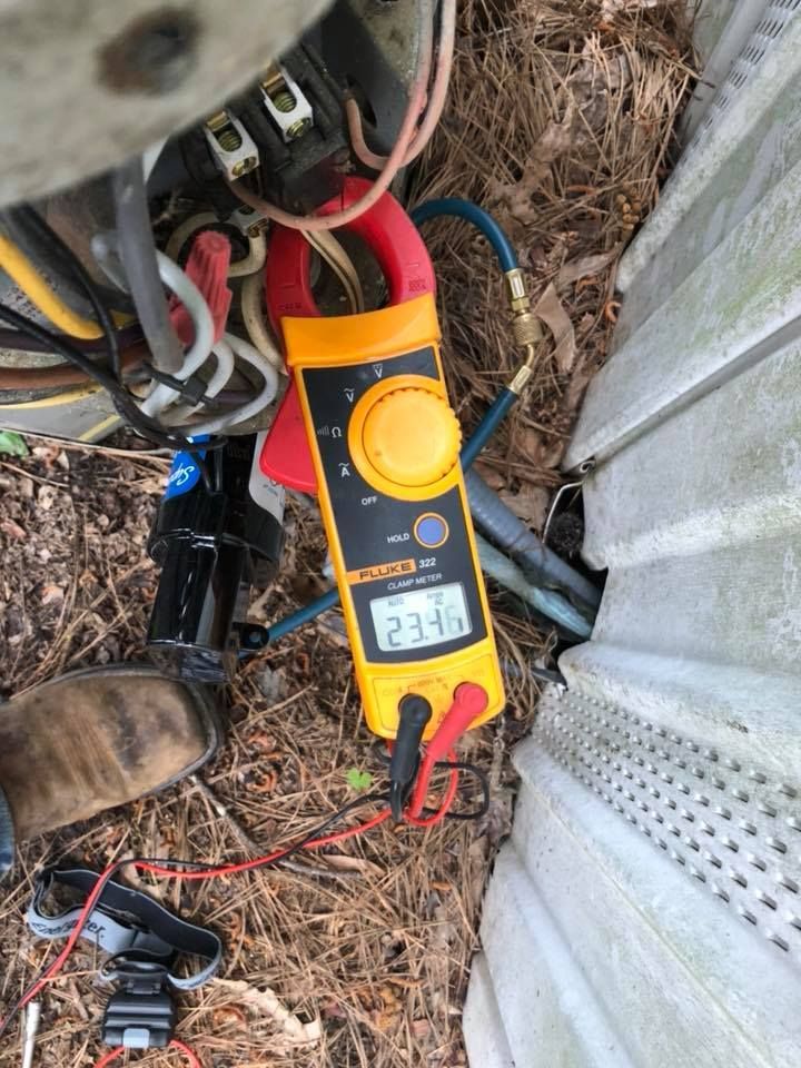 A clamp meter is sitting on the ground next to a wall.