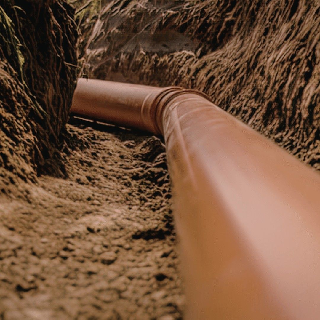 Curtain drain installation intercepting hillside water flow on residential property