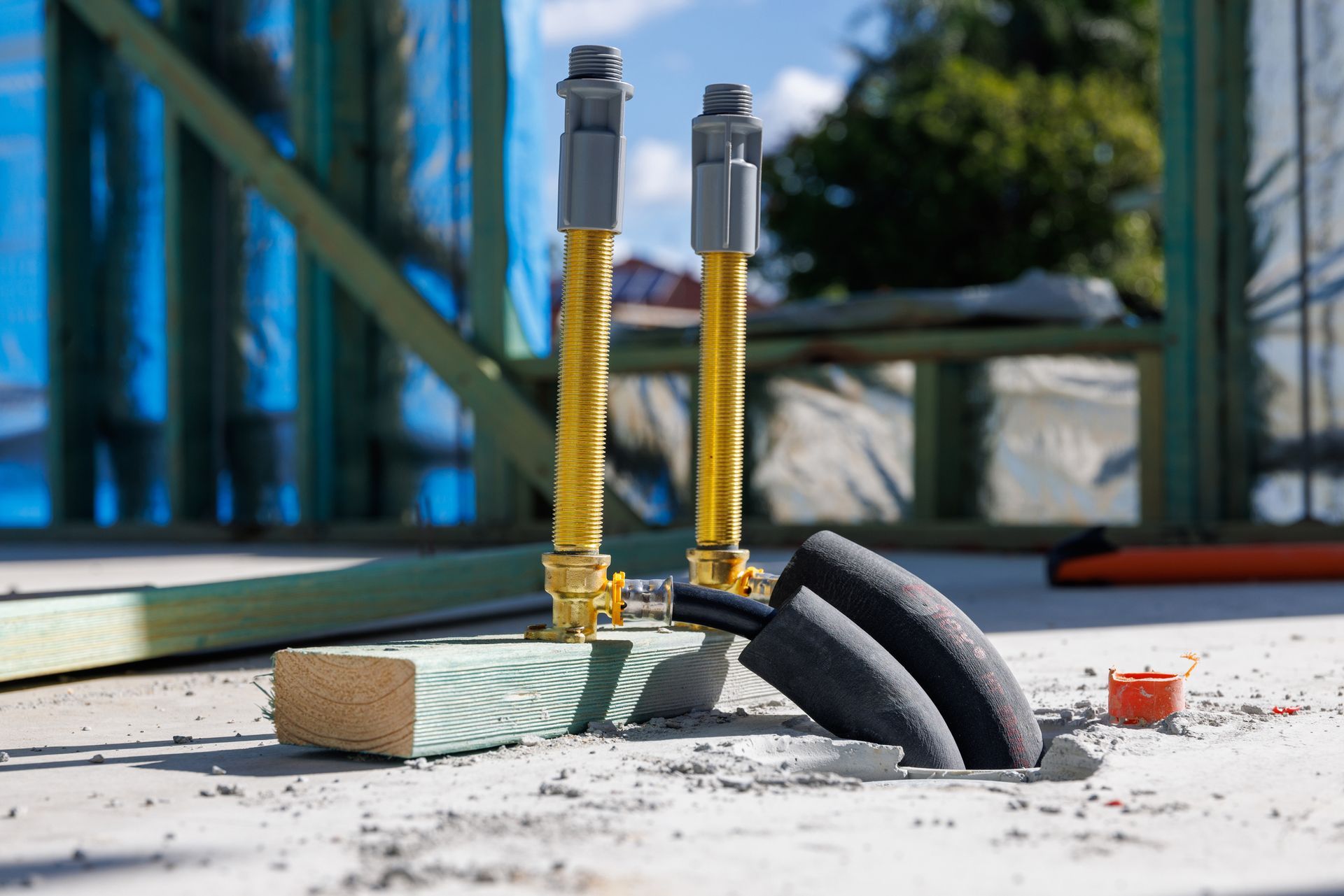 Plumbing pipes at a construction site, with yellow flexible connectors and gray valves.
