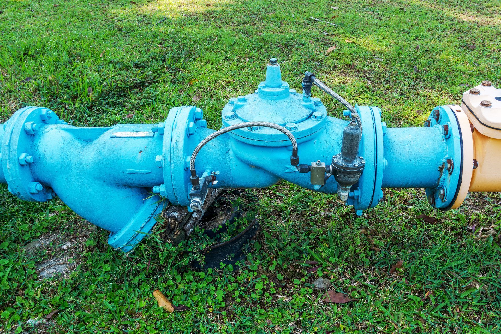 Blue water pipe with attached gauges and yellow pipe on grass.