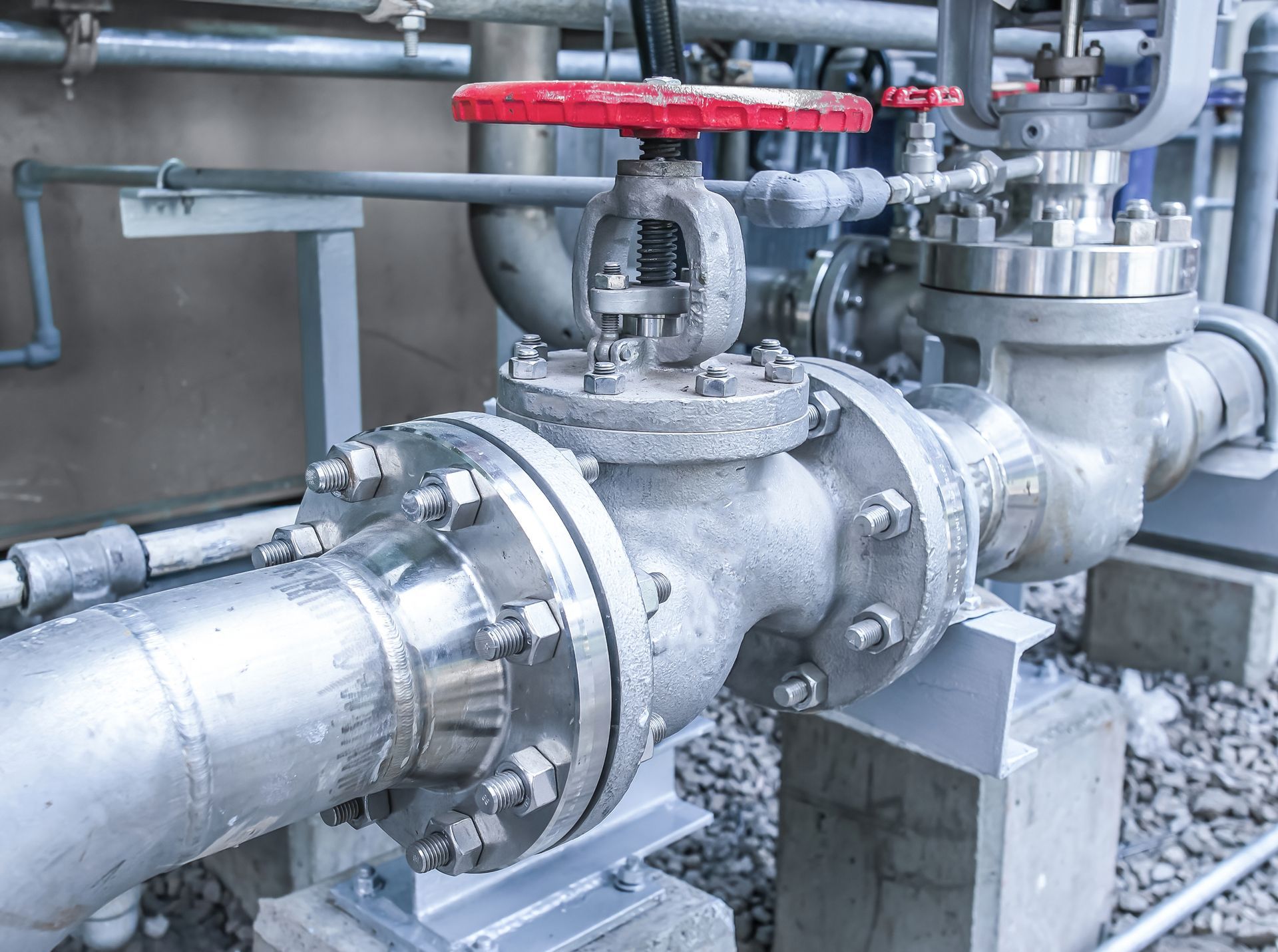 Metal pipe with a red-handled valve, part of an industrial piping system.