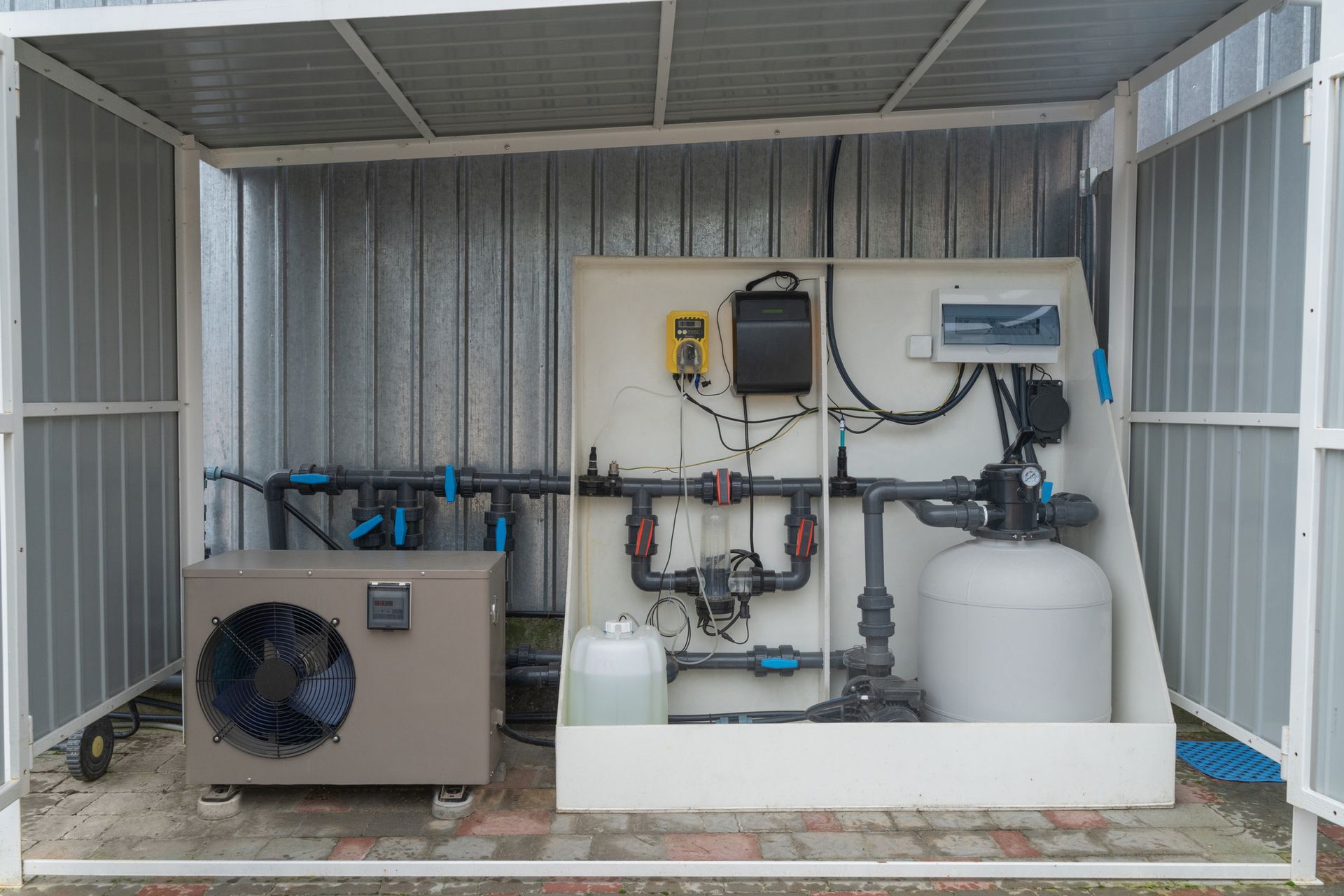 Pool equipment enclosed in a metal shed. Includes a heat pump, filter, and controls.