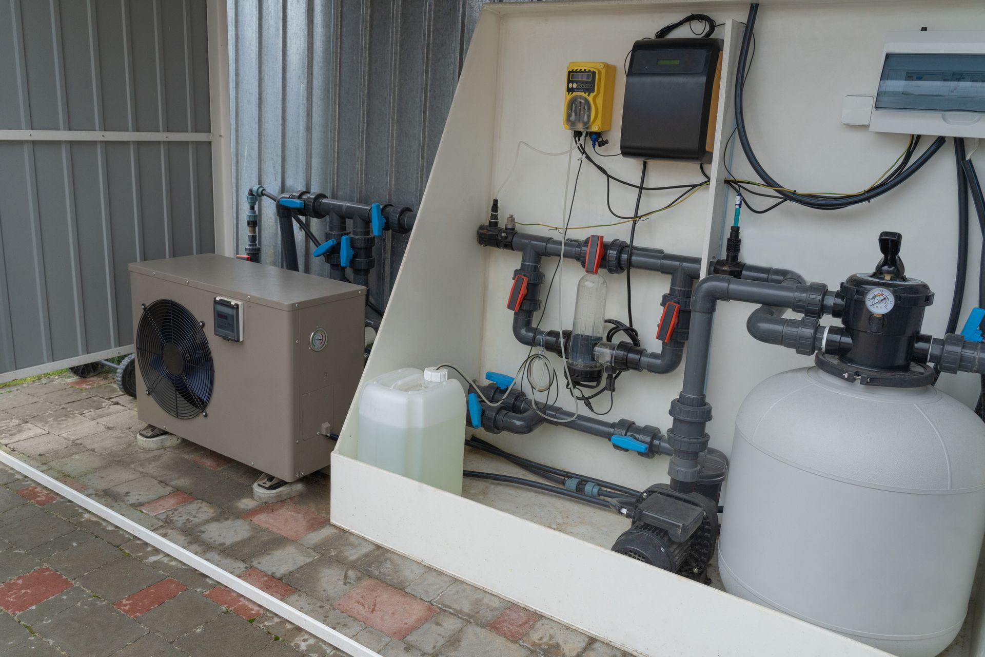 Pool equipment installation: pump, filter, chemical dispenser, and control panel inside a white enclosure, near metal siding.