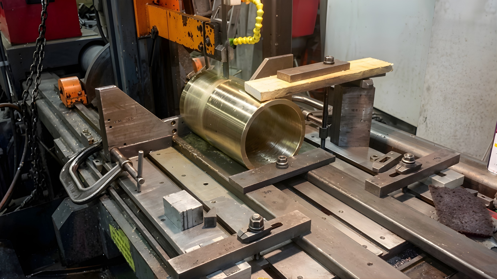 Industrial machine bed with a large gold cylindrical metal part being machined in a workshop