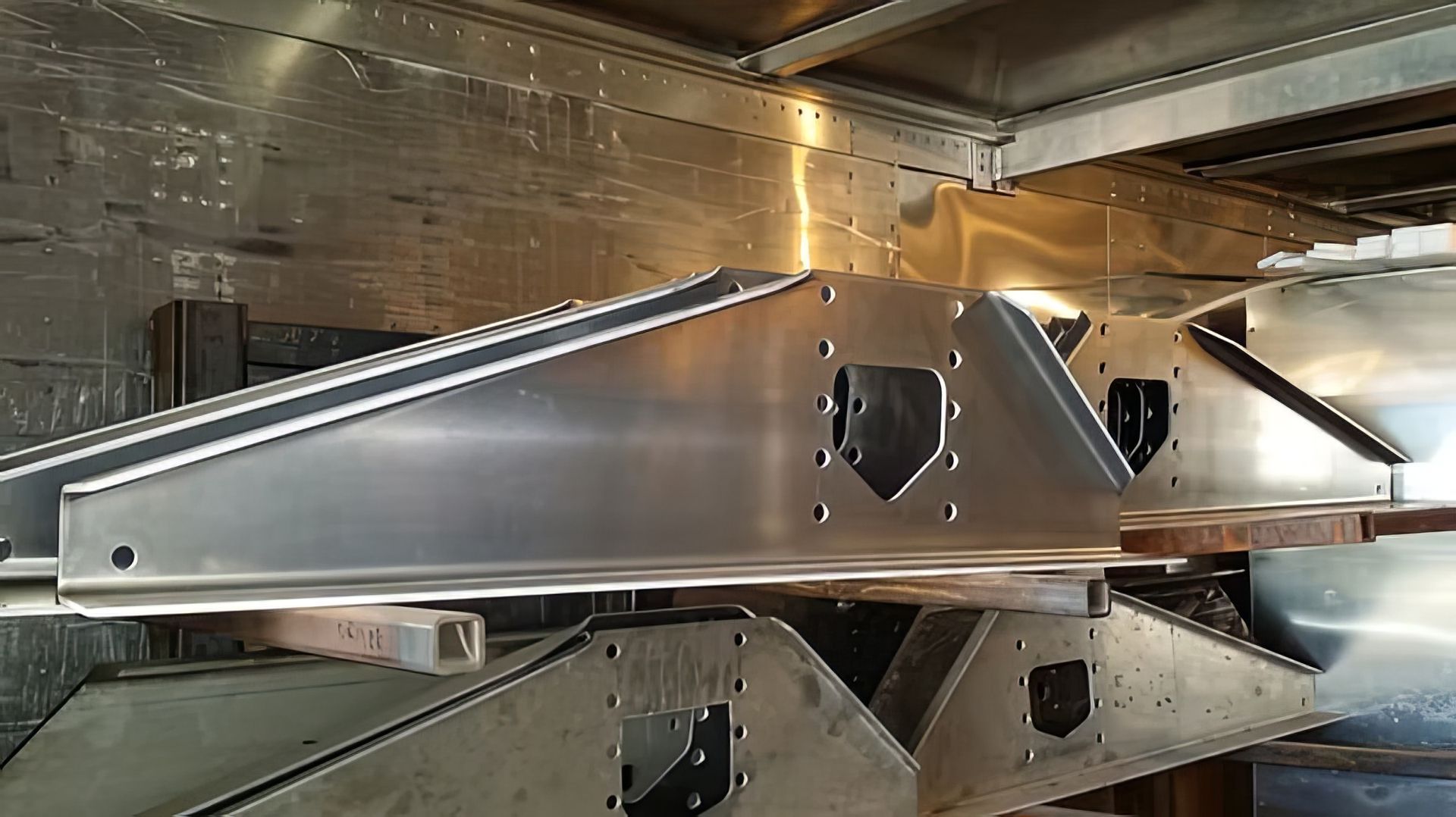 Silver metal aircraft wing structure inside a factory or assembly line.