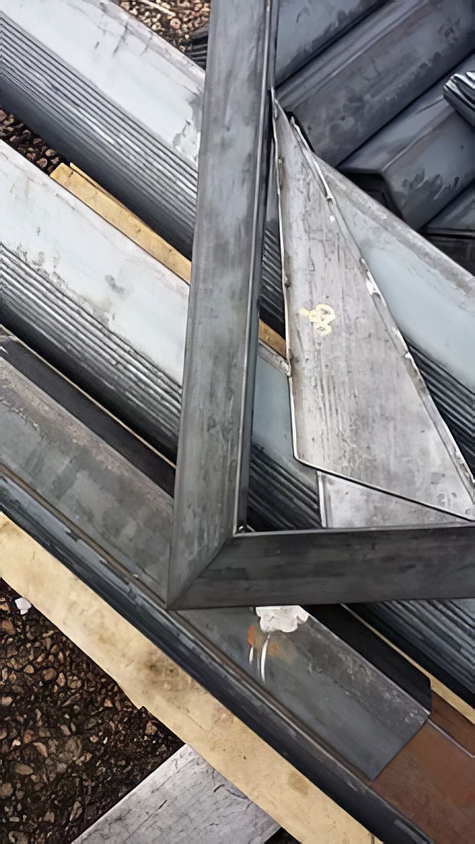 Metal ladder leaning on a corrugated rooftop with triangular framing and weathered panels.