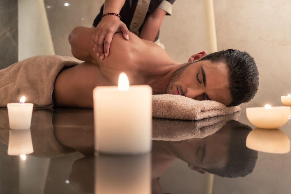 A Man is Getting a Massage in a Spa Surrounded by Candles — Kerry's Body Therapy in Millner, NT
