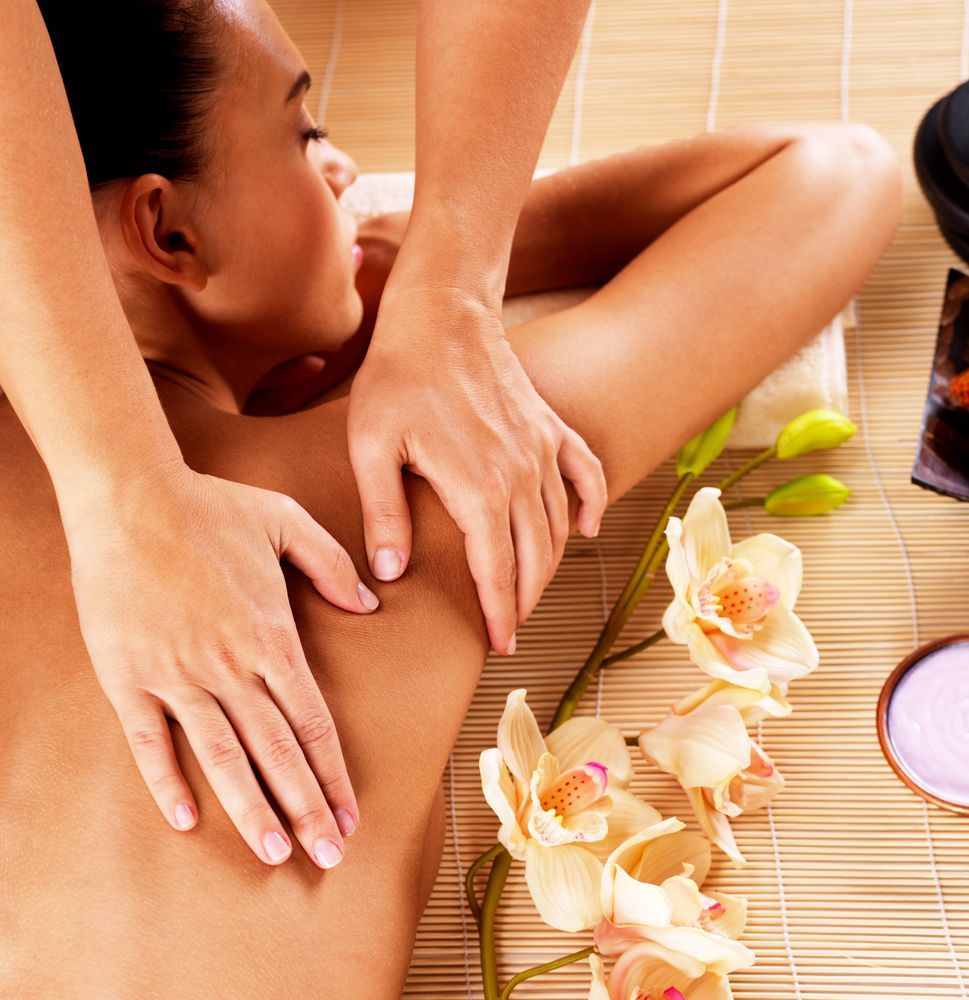 A Woman is Getting a Massage With Flowers in the Background — Kerry's Body Therapy in Millner, NT