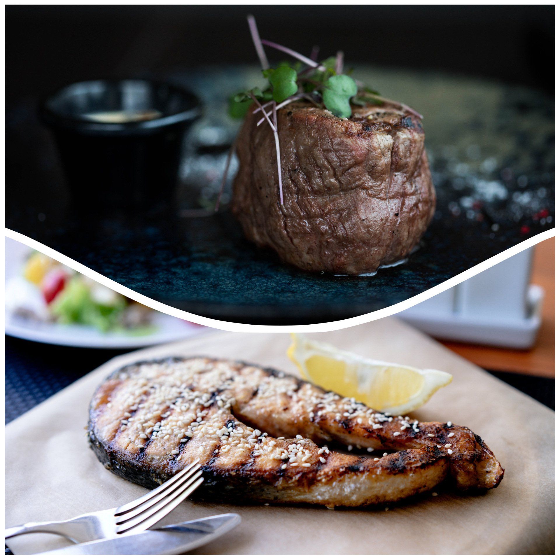 Ein Steak und ein Stück Fisch auf einem Schneidebrett mit einer Gabel.