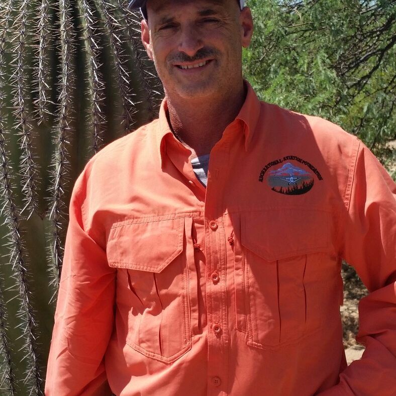 A man wearing an orange shirt with a mountain on it
