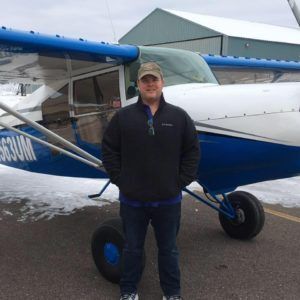A man is standing in front of a blue and white plane with the numbers n633um on the side.