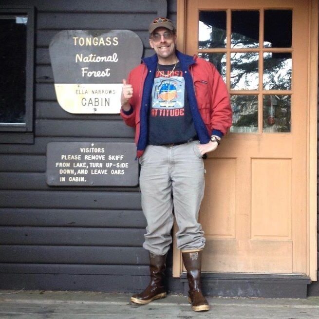 A man stands in front of a sign that says toncass national forest