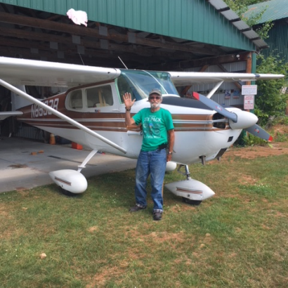A man in a green shirt stands in front of a small plane with n533 on the side