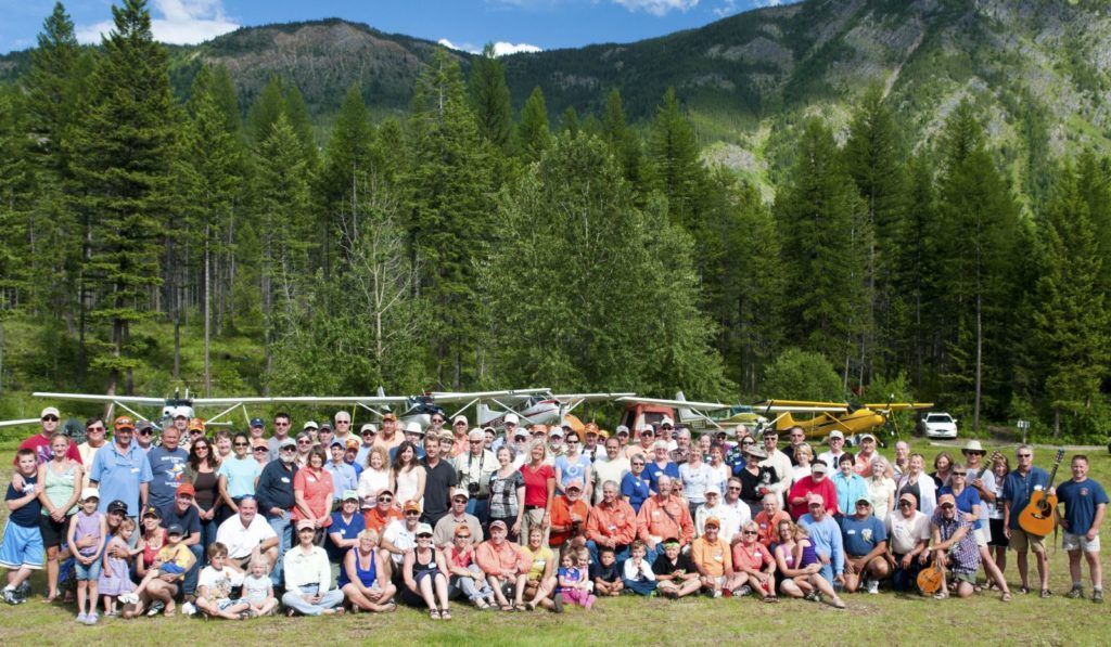 A large group of people are posing for a picture in front of a mountain.