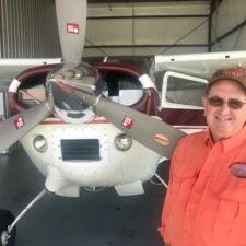 A man is standing in front of a small plane in a hangar.