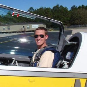 A man wearing sunglasses is sitting in a yellow and white plane