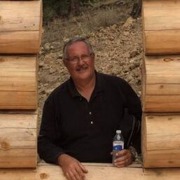 A man is sitting in a log cabin holding a bottle of water.