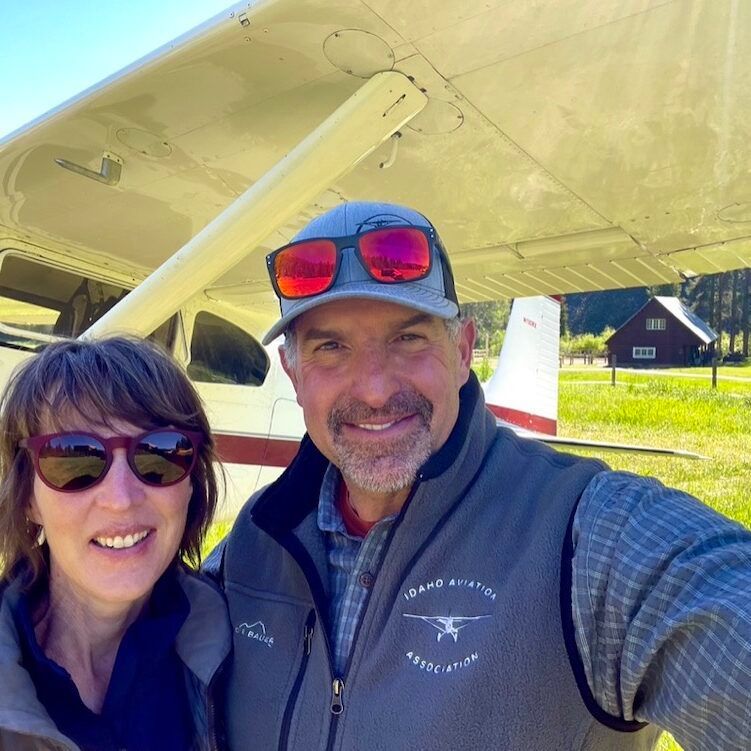 A man and a woman are posing for a picture in front of an airplane