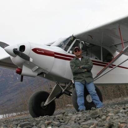 A man is standing next to a small propeller plane