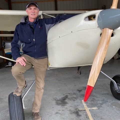 A man is standing next to a small plane in a hangar.