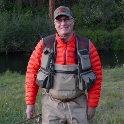 A man in an orange jacket is holding a fishing rod