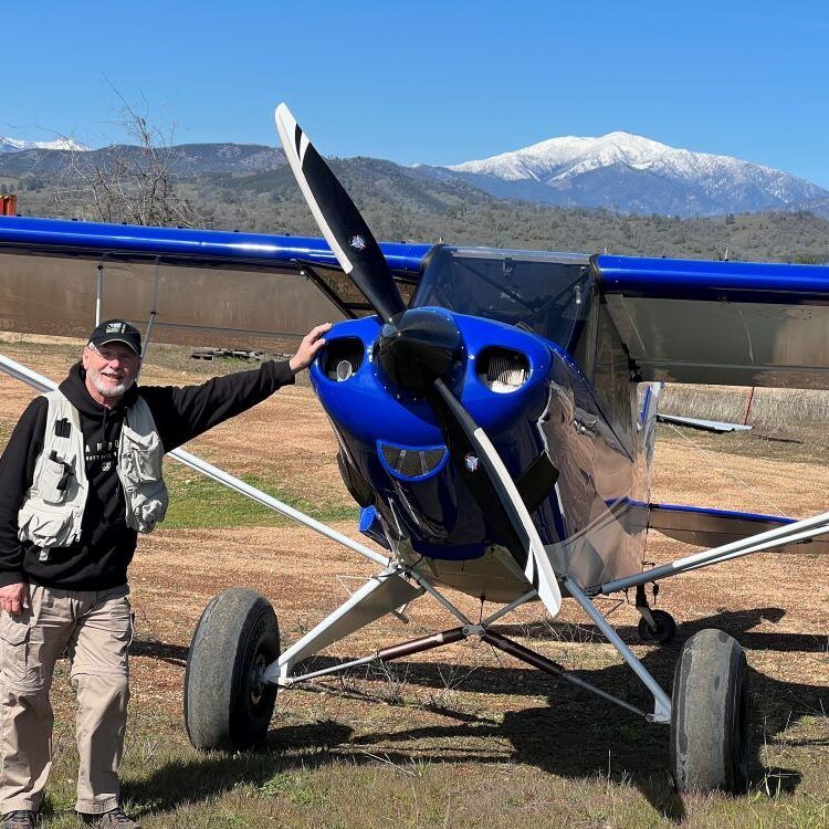 A man is standing in front of a small blue plane