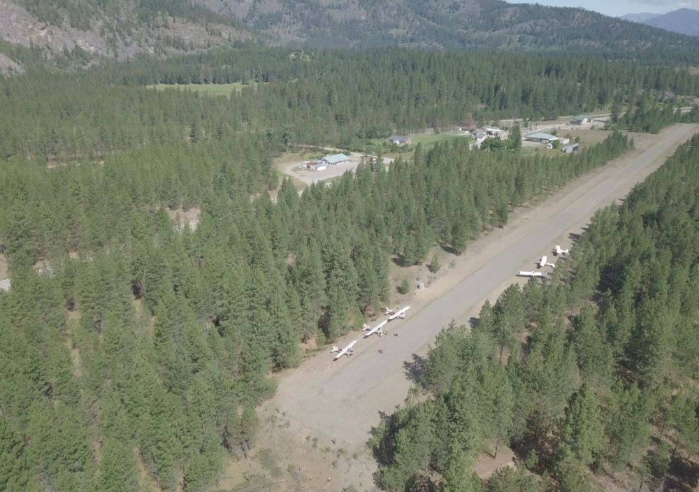 An aerial view of a runway surrounded by trees and mountains.