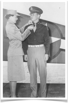 A woman is putting a medal on a man 's uniform