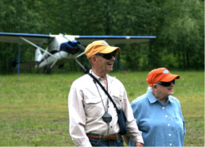 A man and a woman are standing in front of a small plane