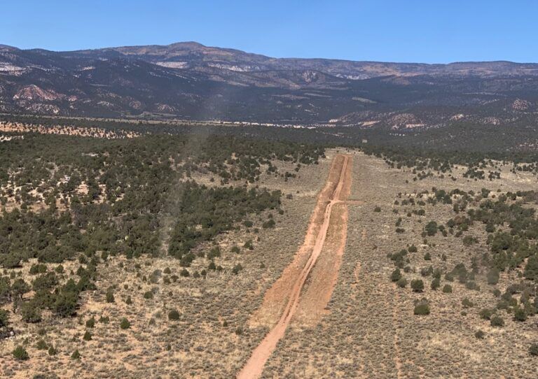 An aerial view of a dirt road in the desert with mountains in the background