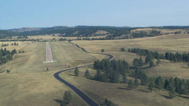 An aerial view of a runway in the middle of a field surrounded by trees.