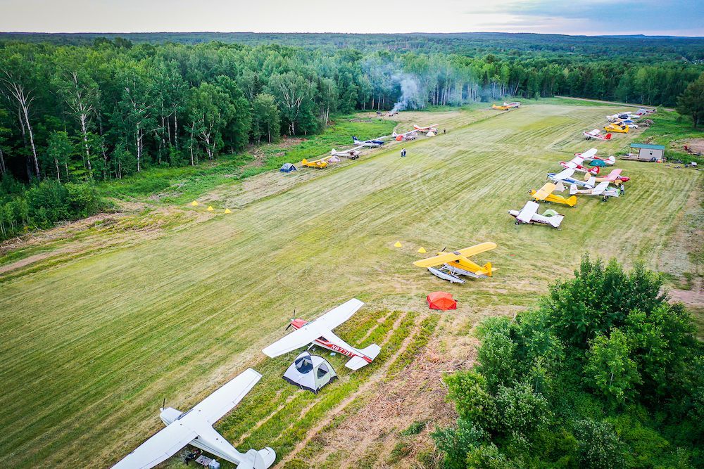 A group of small planes are parked in a field.