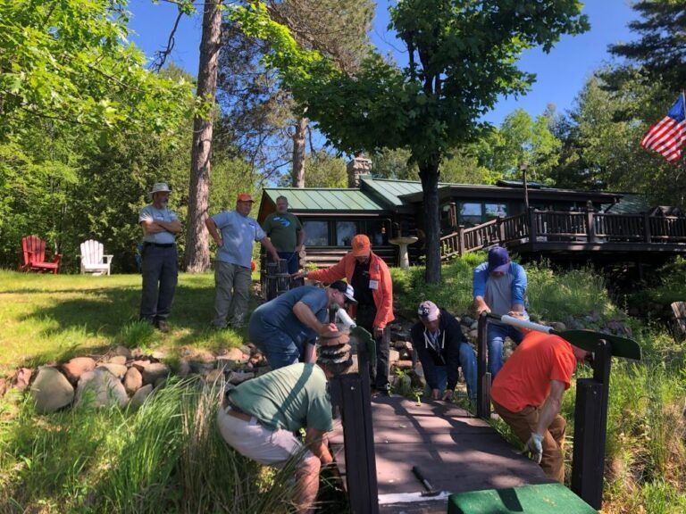 A group of people are working on a bridge in front of a house.