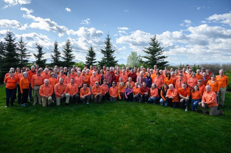 A large group of people wearing orange shirts are posing for a picture.