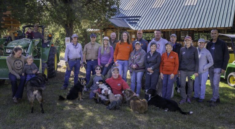 A group of people and dogs are posing for a picture in front of a house.