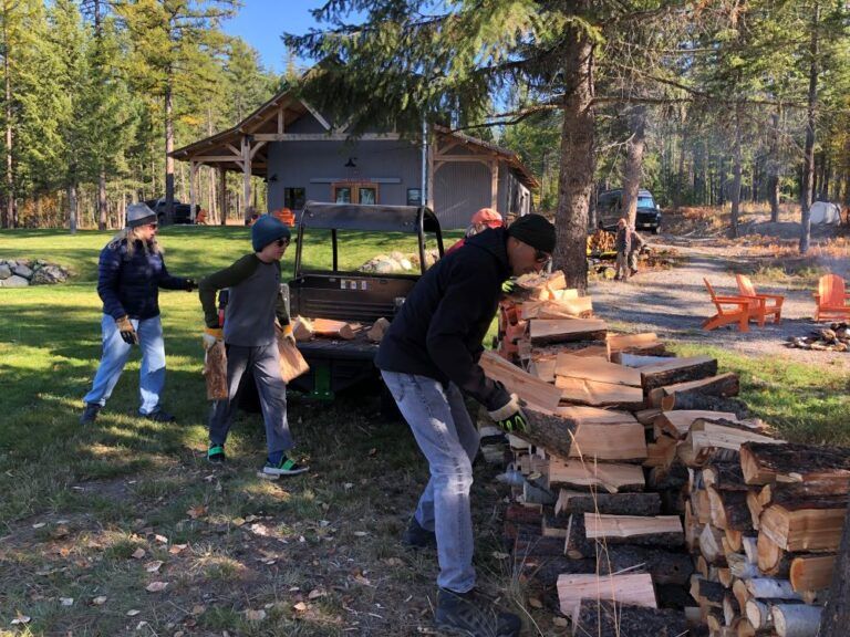 A group of people are standing around a pile of logs.