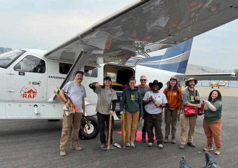 A group of people are standing in front of a small plane.