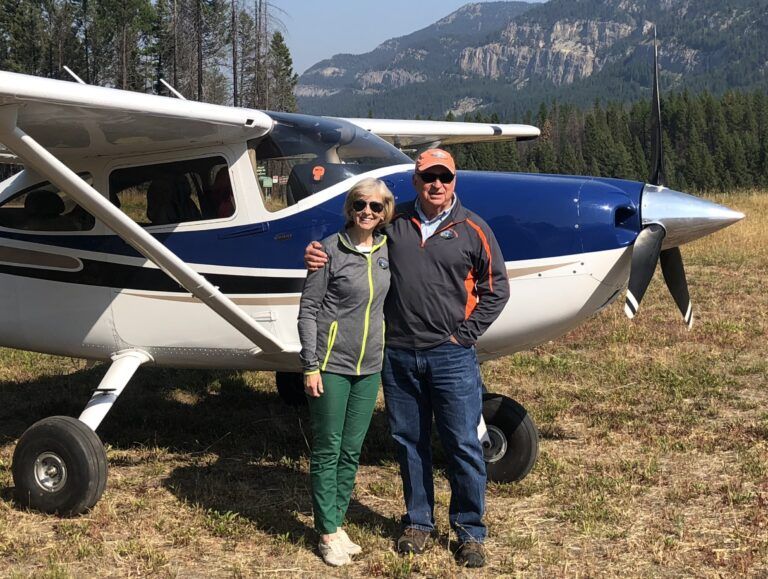 A man and a woman are standing in front of a small plane.
