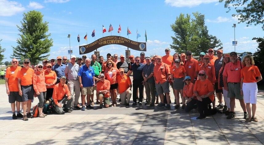 A large group of people in orange shirts are posing for a picture.