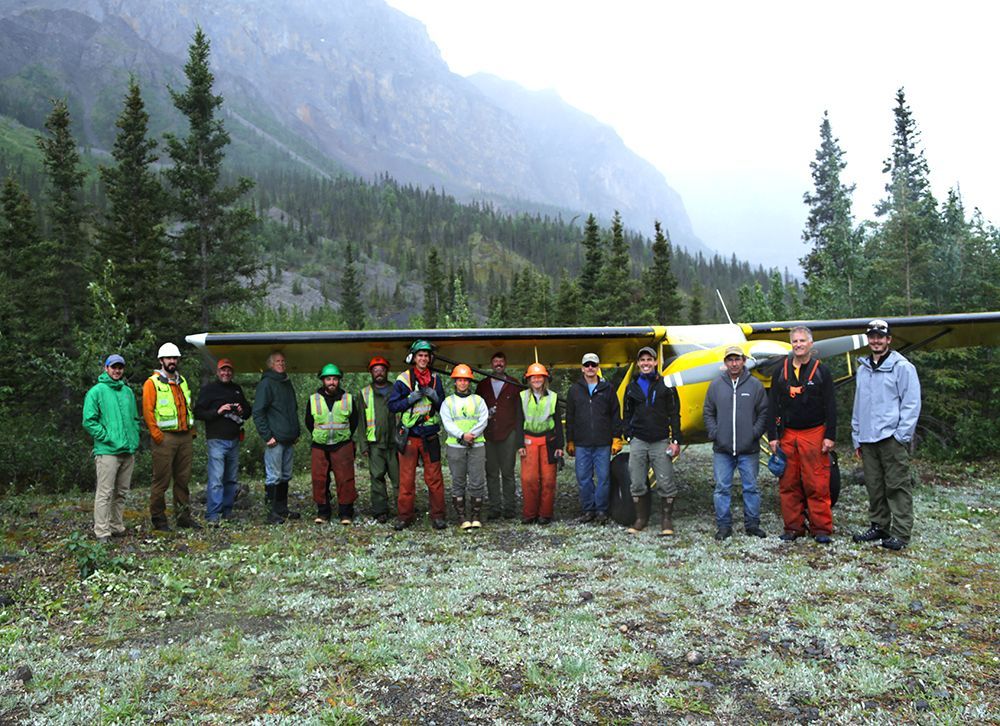 A group of people standing in front of a yellow plane