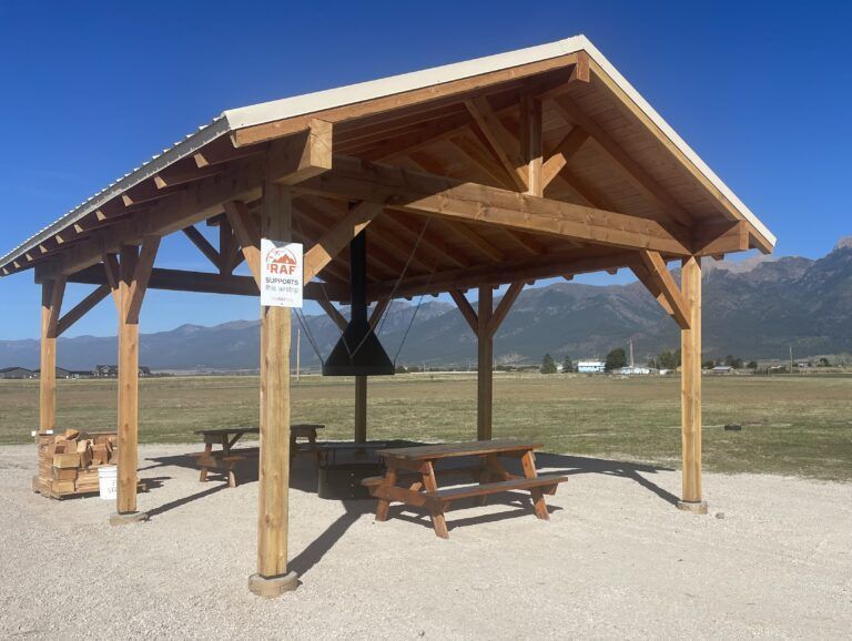 A wooden shelter with a picnic table underneath it