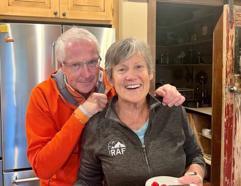 A man is putting his arm around a woman in a kitchen.