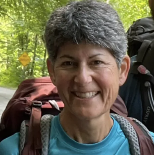 Man in plaid shirt and cap, next to a yellow floatplane, holding its wing.