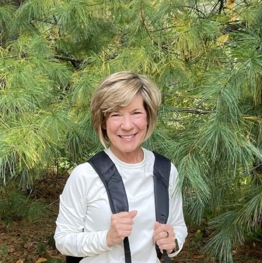 Man standing by an orange and white plane on a snowy runway.