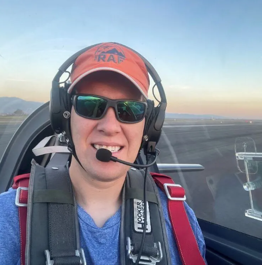 Woman in airplane, smiling with dog, looking out the window.