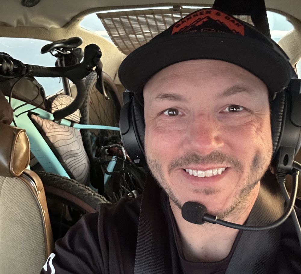 A man wearing headphones and a hat is smiling in a car.