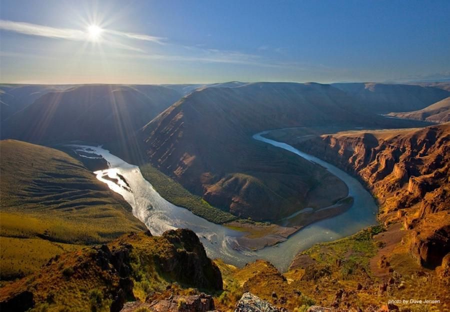 A river flowing through a canyon with the sun shining through it
