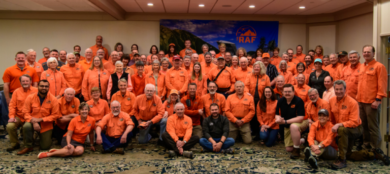 A large group of people wearing orange shirts are posing for a picture.