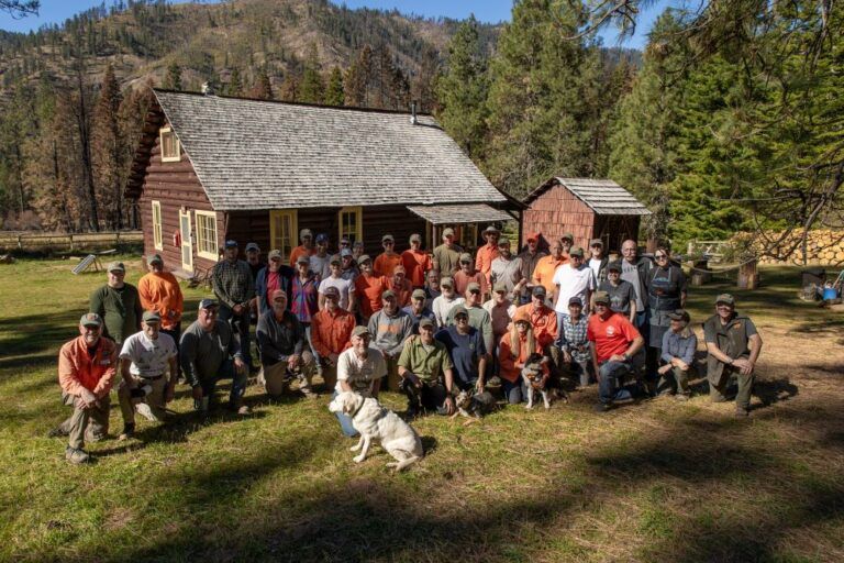 A large group of people are posing for a picture in front of a cabin.